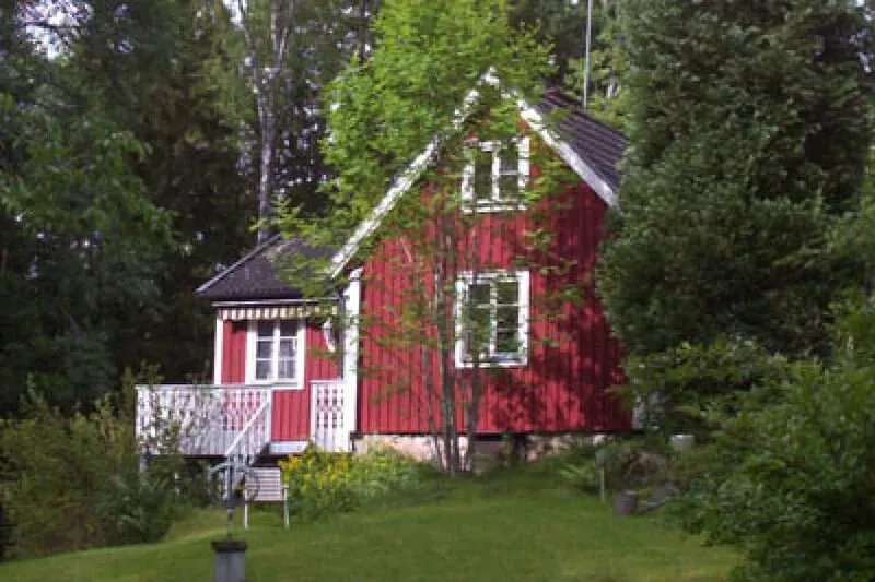 Red and white cottage with a boat not far from the lake