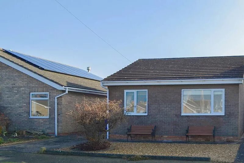 Modern accommodation with sun room and patio overlooking a small lake.