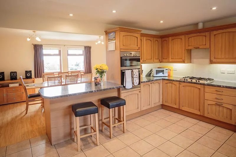 Family house surrounded by lawn and woodlands with countryside views.
